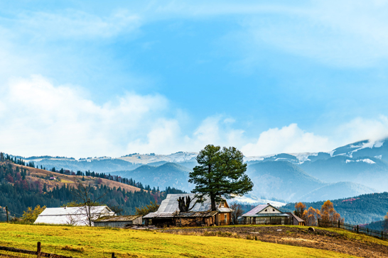 Beautiful colorful forests covering the Carpathian mountains and a small village against the background of a warm autumn sky