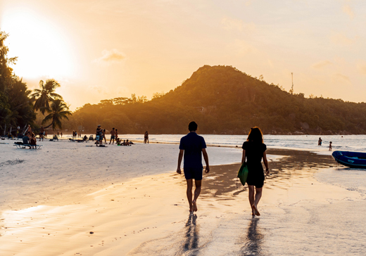 rear-view-of-people-walking-on-tropical-sandy-beach