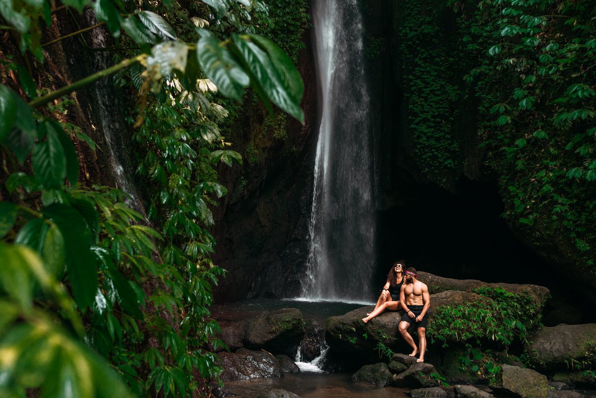 Affectionate couple enjoying a lush jungle waterfall view in Bali during rainy season
