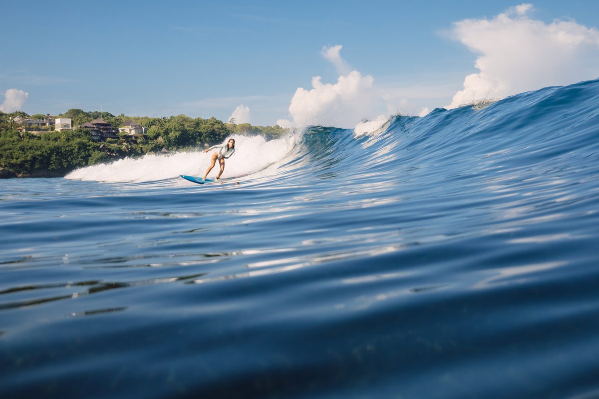 Surfer riding a wave on a sunny day at Uluwatu Bali during golden hour dry season