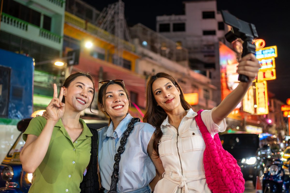 Young Asian woman travel vlogger using camera to record travel content in Thailand