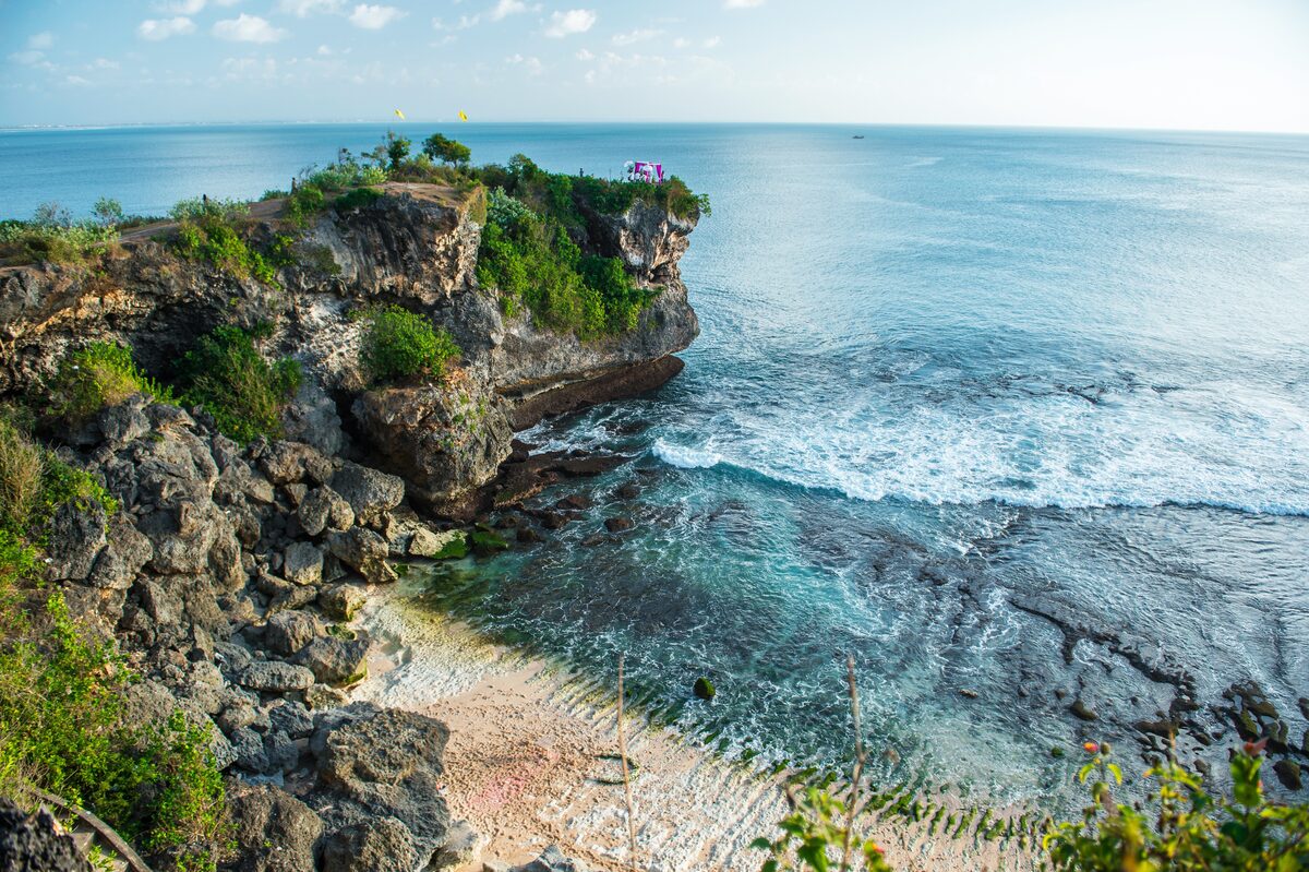 Traveler sitting on Bingin Beach with turquoise water and limestone cliffs