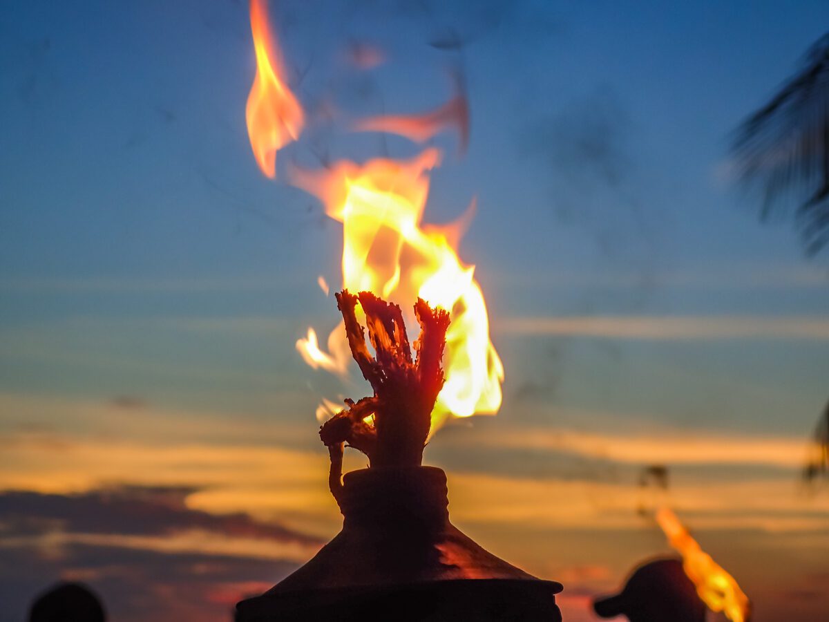 Kecak fire dance performers at Uluwatu temple with the ocean at sunset