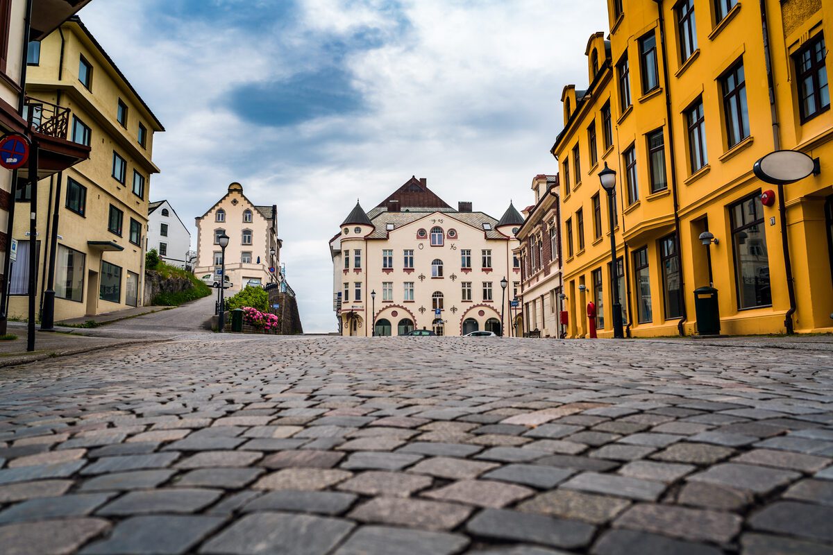 Quiet European cobblestone street in autumn with golden leaves — the best time to visit Europe on a budget